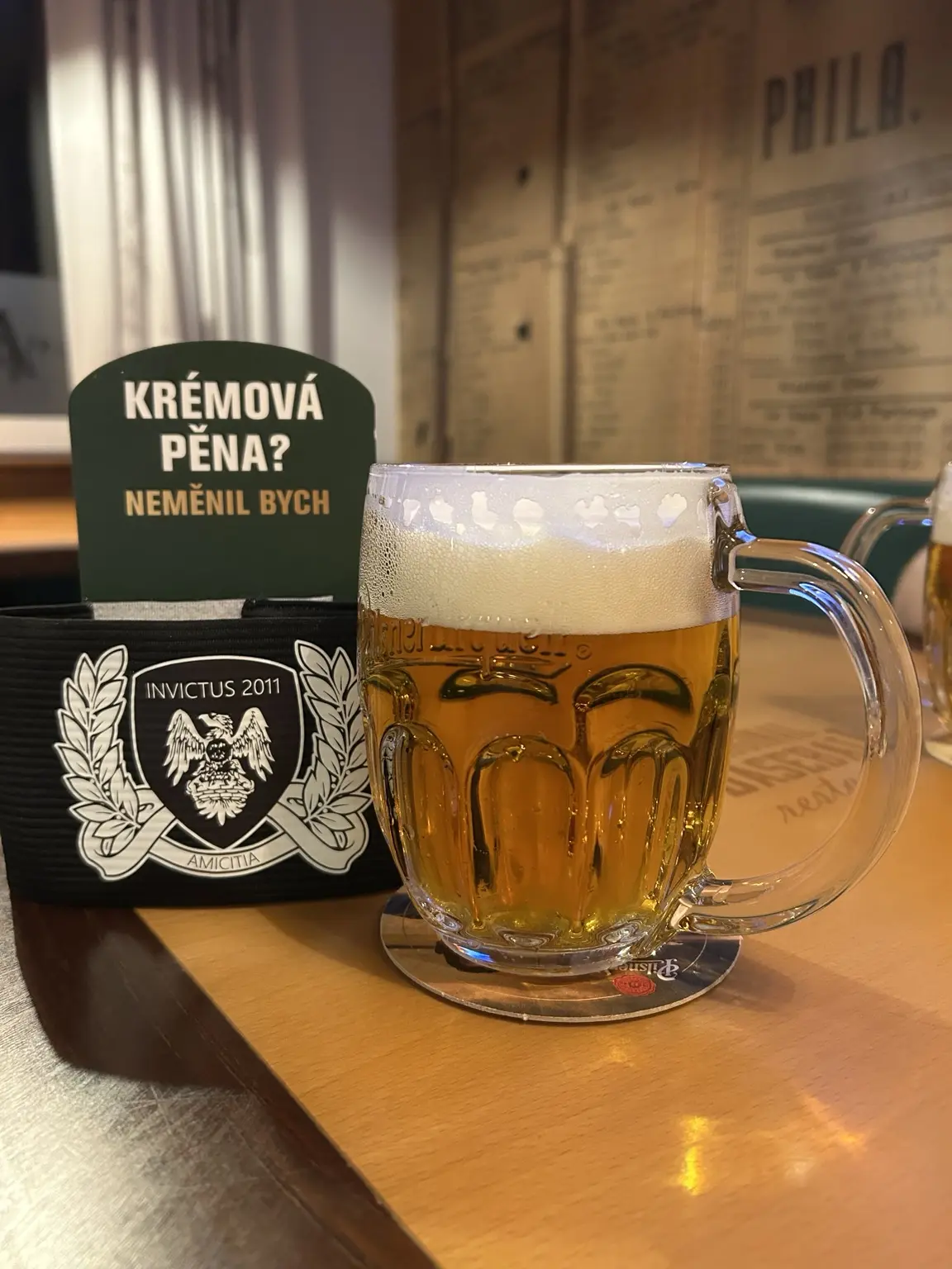 Sklenice piva vedle kapitánské pásky Invictus 2011