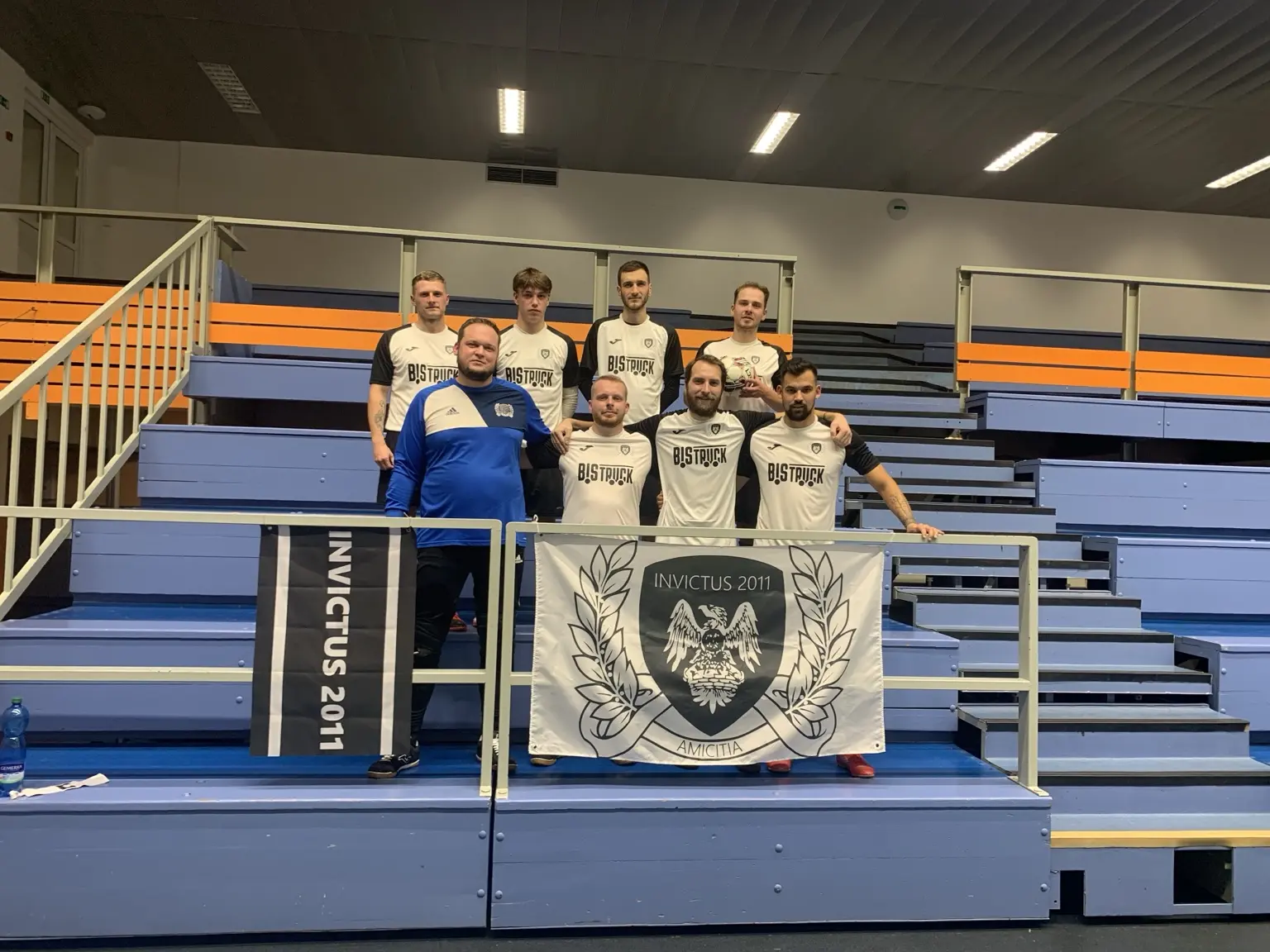 Hráči Invictu na tribuně s velkou a malou klubovou vlajkou